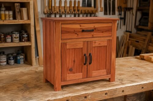 Mueble auxiliar de madera de estilo rústico con un cajón superior, dos puertas y tiradores metálicos, fabricado artesanalmente en un taller de carpintería.